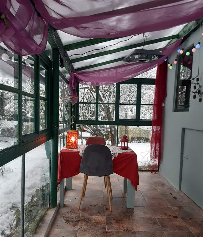 Az üvegház télen, piros terítős asztallal és mécsesekkel